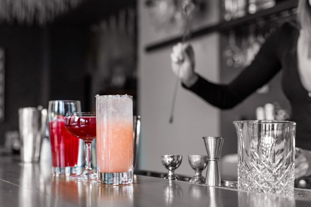 A few of Vidrio's Classic mixed drinks, in Downtown Raleigh NC. With a black and white background and surroundings. Highlighting the vibrance of the drinks.