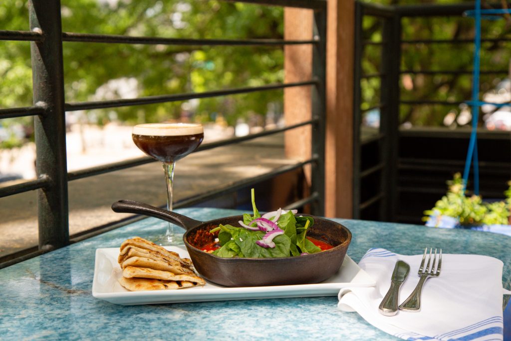 LM Restaurants' Taverna Agora, Downtown Raleigh NC, Brunch Dish Shakshuka with a beverage and rooftop scenery