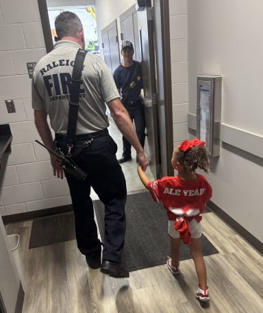 Garner NC FD with CAH child volunteering. NC Carolina Ale House teams visit first responders and medical staff for Labor Day 2025 to bring food to share and love.